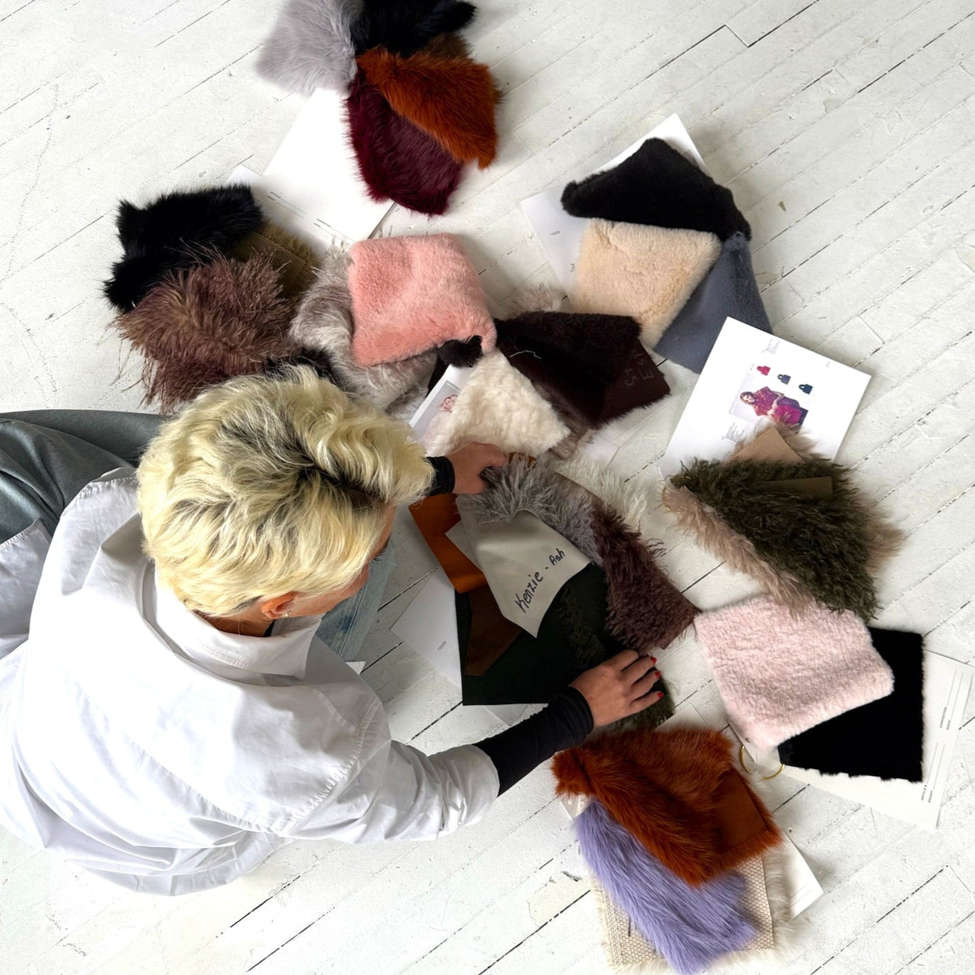 FREED founder, Marissa Freed, crouching in a pile of fabric swatches.