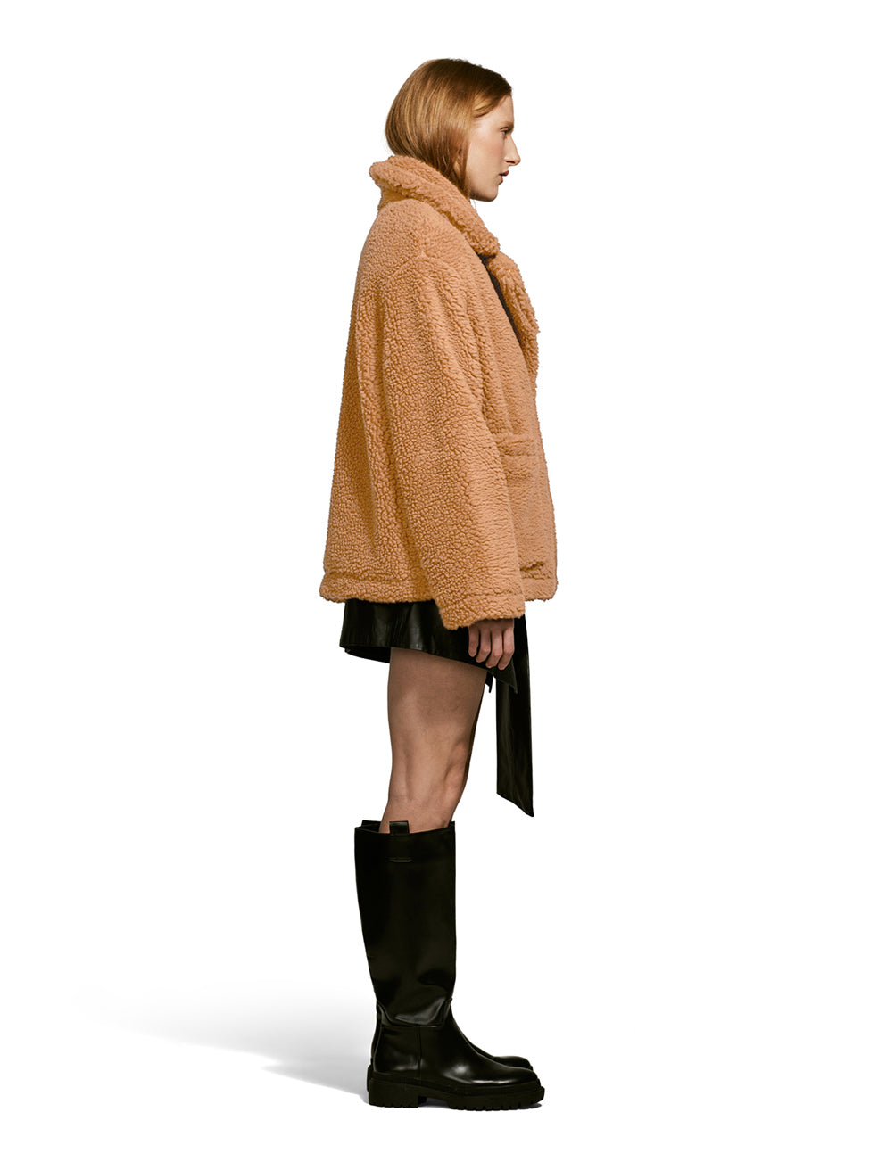 Model wearing the Robin, a hip-length teddy-inspired faux-fur sherpa shell in camel color from the side.