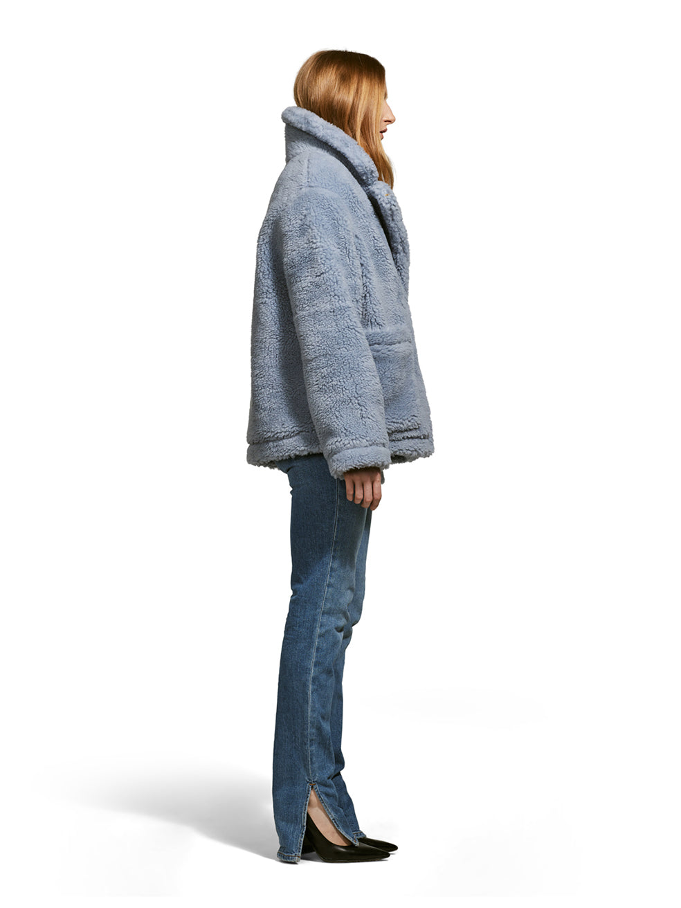 Model wearing the Robin, a hip-length teddy-inspired faux-fur sherpa shell in sky color from the side.